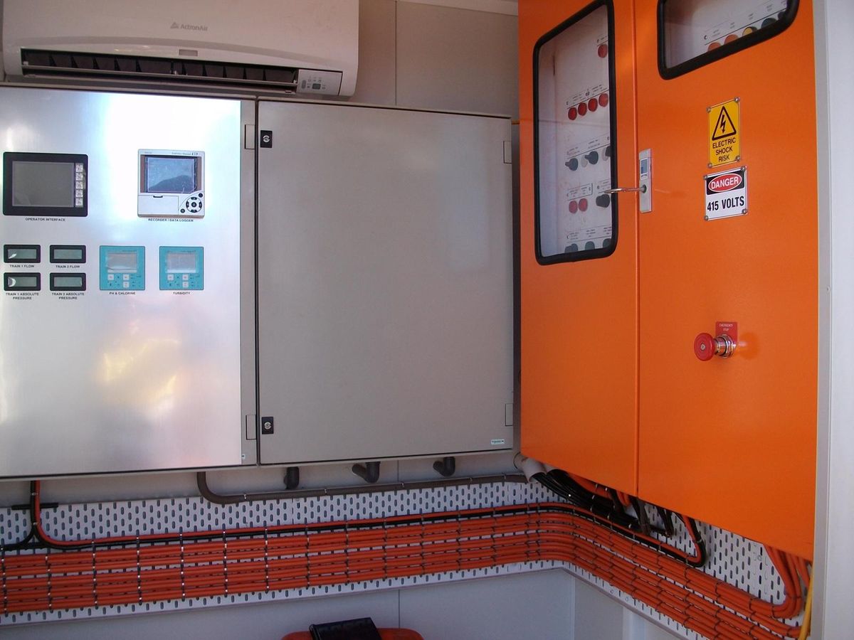 Inside a plant switchroom: the operator control panel with its display screens, and an orange switchboard cabinet marked 415 volts.