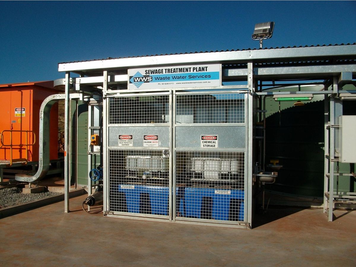 A Waste Water Services sewage treatment plant on site, its signage mounted above a caged chemical storage bay.